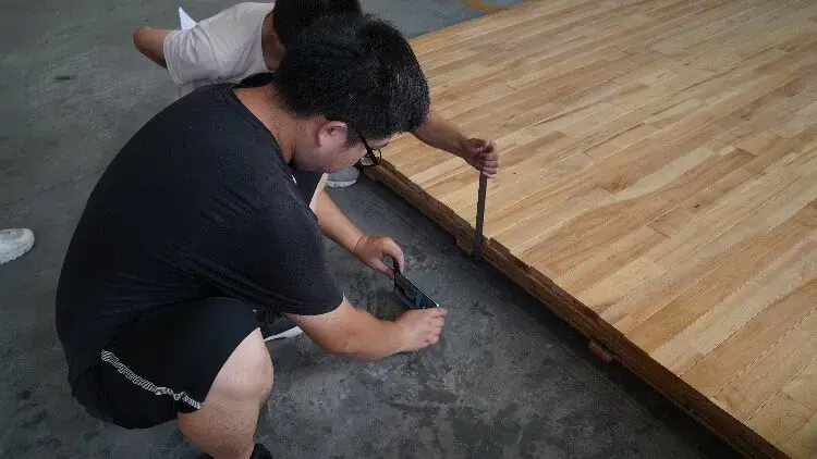 Staff members inspect the thickness of the sports wood flooring Staff members inspect the thickness of the sports wood flooring